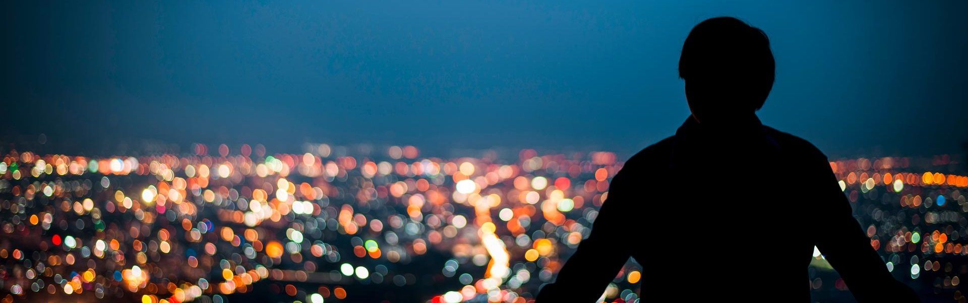 Silhouette of man looking above the city in the night